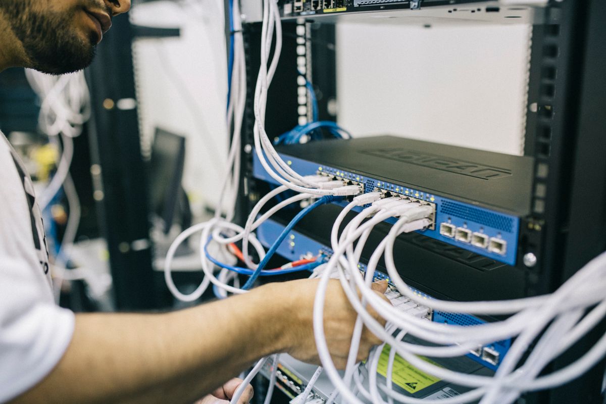 Technician terminating network cabling in a server rack